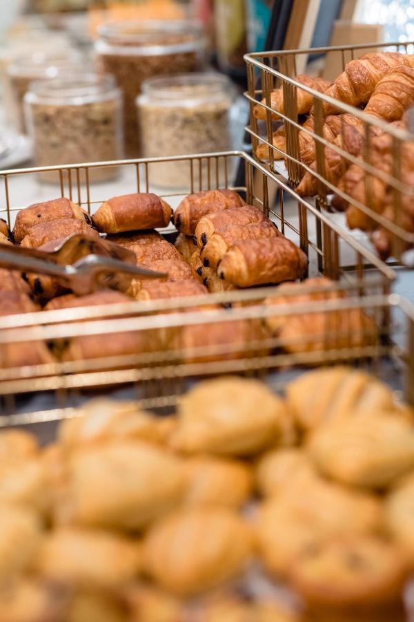 Hotel Le Plaza Brusel Exteriér fotografie The photo shows a selection of baked pastries arranged in metal wire baskets. There are various types of pastries, including croissants and chocolate-filled rolls. Some pastries appear flaky and golden-brown, while others have a slightly darker color
