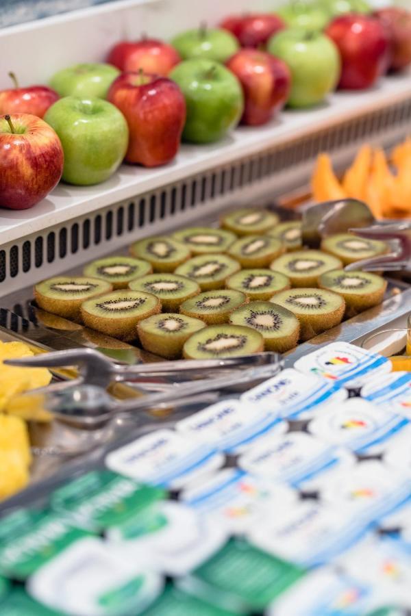 Hotel Le Plaza Brusel Exteriér fotografie The photo shows a selection of sliced kiwifruit arranged neatly on a metal tray. The slices reveal the green flesh with tiny black seeds in the center. In the background, there are also whole apples, and nearby, there seems to be additional fruit, po