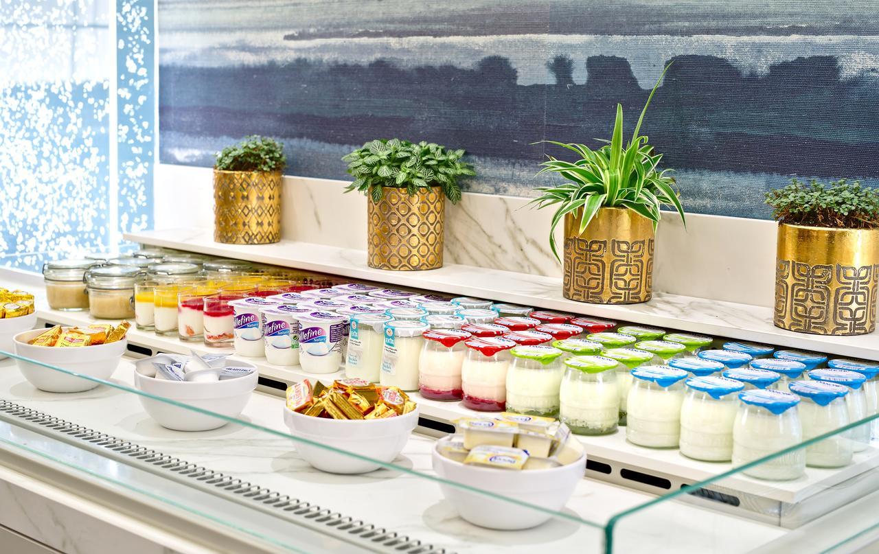 Hotel Le Plaza Brusel Exteriér fotografie The photo shows a beautifully arranged dessert display. There are multiple jars of different colored desserts lined up, including layers of cream and jelly-like textures. In front of these jars, there are small bowls containing toppings or additional